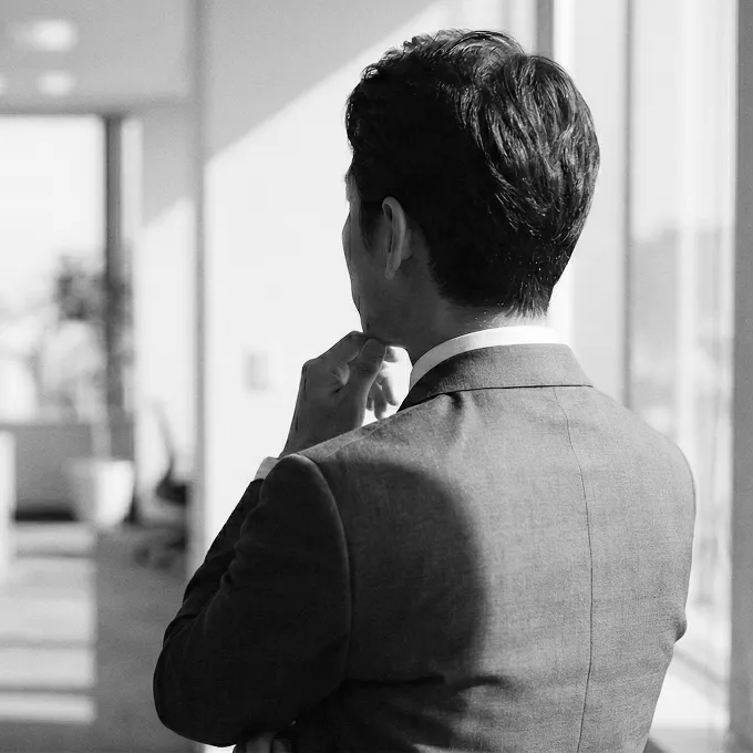スーツを着た男性が考え事をする後ろ姿