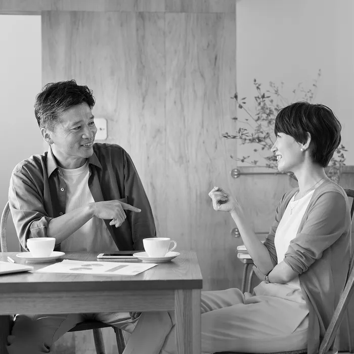 不動産売買の相談や契約をイメージさせるリビングで穏やかに話し合う夫婦とテーブルに置かれた資料や飲み物