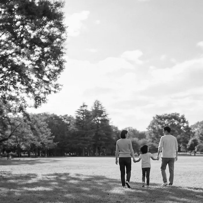 不動産購入後の幸せな家族生活を想起させる緑豊かな住環境の公園で散歩を楽しむ仲睦まじい親子の風景